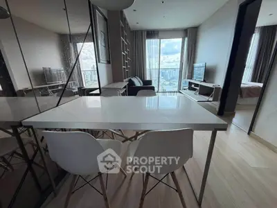 Modern apartment interior with dining area, living room, and city view from large windows.