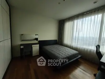 Spacious bedroom with large window and modern furnishings