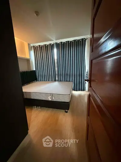 Cozy bedroom with wooden flooring and striped curtains, perfect for restful nights.