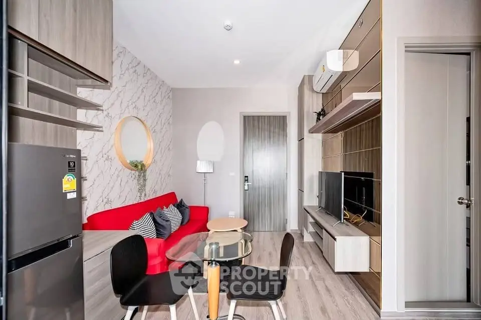 Modern living room with stylish decor and open layout, featuring a red sofa and sleek entertainment center.