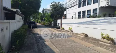 Charming residential street view with lush greenery and modern buildings, perfect for urban living.