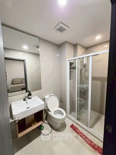 Modern bathroom with glass shower and sleek fixtures in contemporary apartment.
