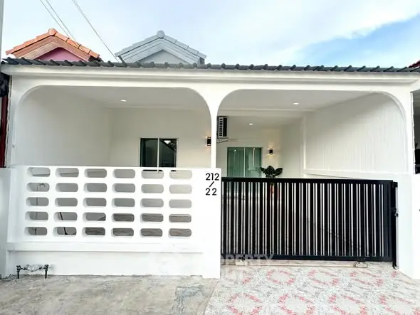 Charming single-story white house with modern facade and gated entrance, perfect for cozy living.