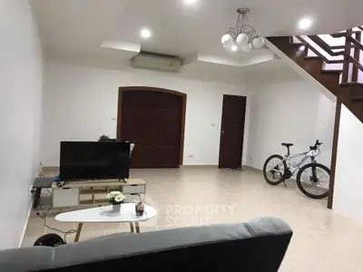 Spacious living room with modern decor and staircase, perfect for relaxation and entertainment.