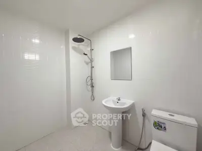 Modern minimalist bathroom with sleek white tiles and contemporary fixtures.