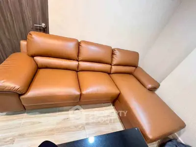 Modern living room with stylish brown leather sectional sofa and wooden flooring