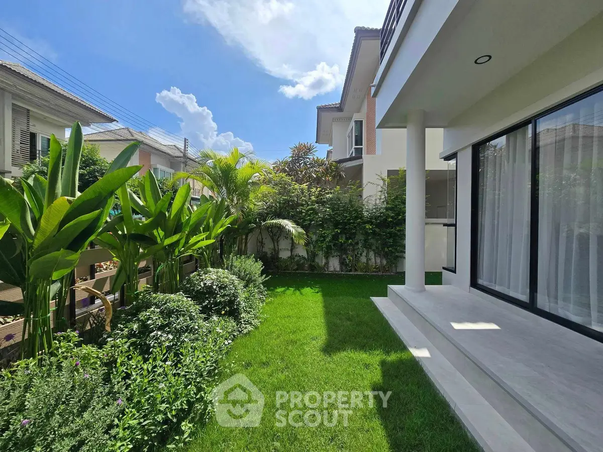 Beautiful garden view of modern house with lush greenery and clear blue sky.