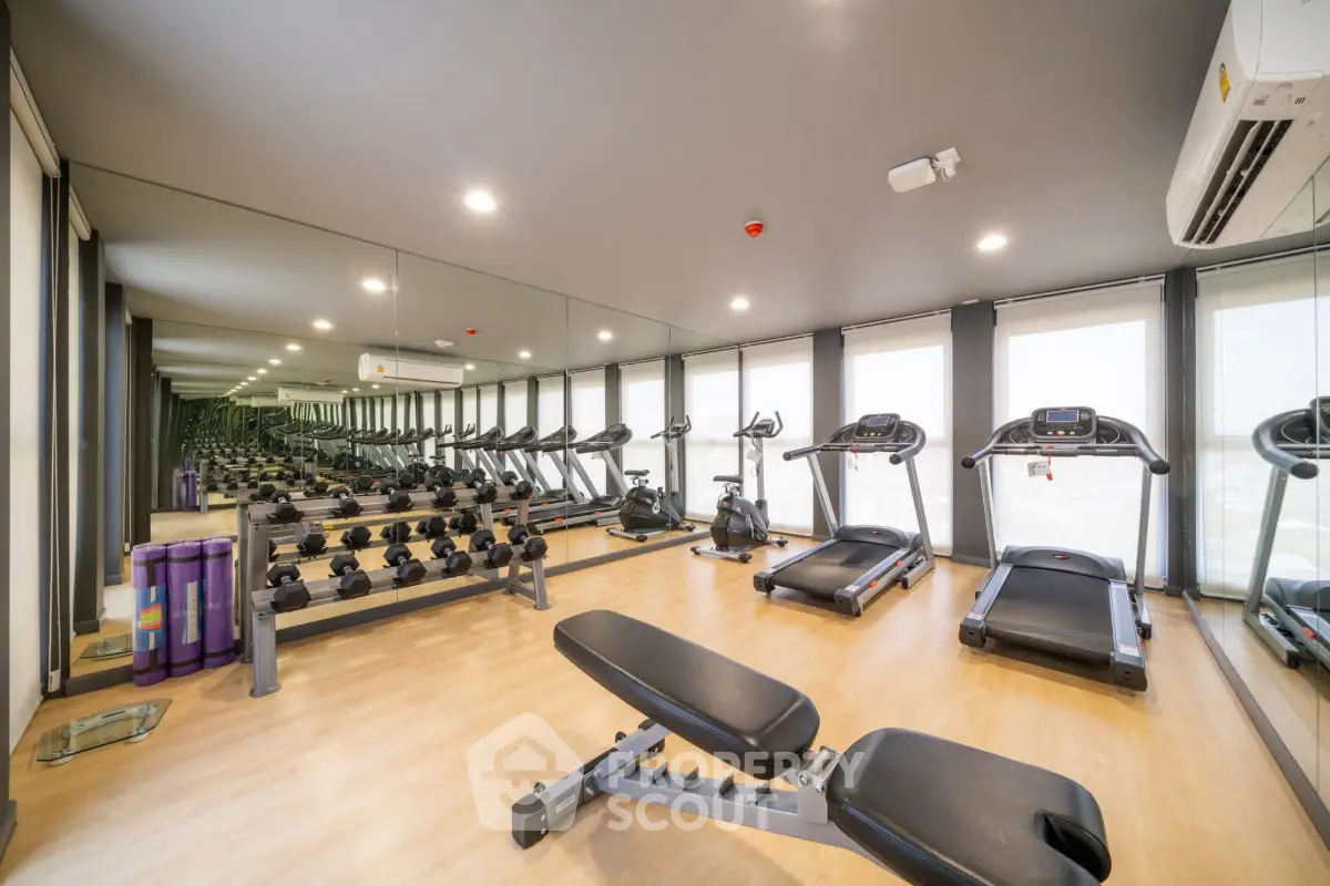 Modern gym with state-of-the-art equipment and mirrored walls in luxury apartment building.