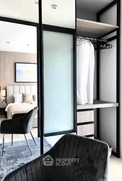 Modern bedroom with open closet and stylish chairs, featuring elegant decor and a cozy atmosphere.