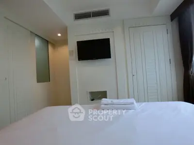 Modern bedroom with minimalist decor and wall-mounted TV