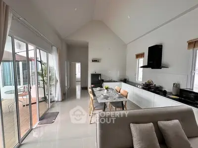 Spacious modern kitchen and dining area with open layout and large windows leading to a balcony.