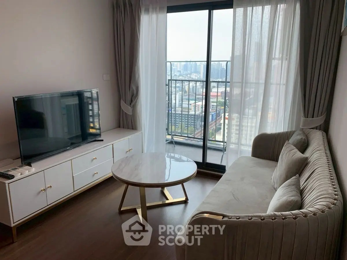 Modern living room with elegant sofa, TV, and city view from balcony.