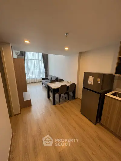 Modern living room with dining area and sleek kitchen in open layout apartment.
