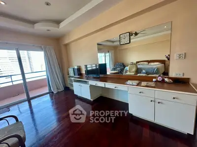 Spacious bedroom with elegant wooden flooring and large mirror, featuring a cozy balcony view.