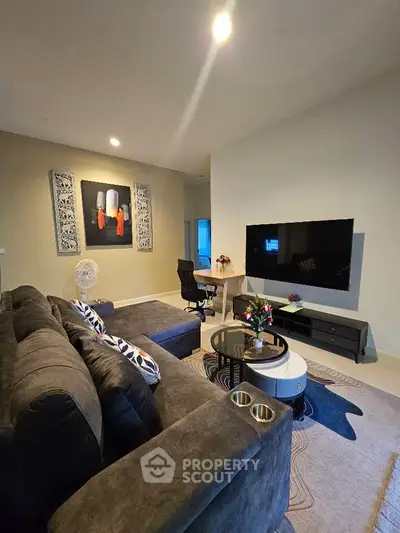 Modern living room with stylish decor and large TV, perfect for relaxation.