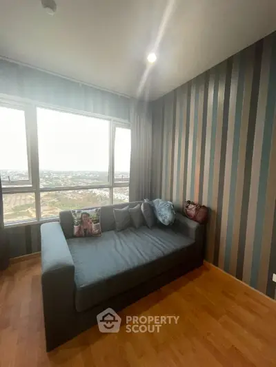 Modern living room with striped wallpaper and large window offering stunning city views.