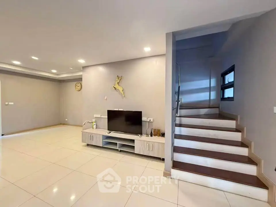Spacious modern living room with sleek design and staircase, perfect for contemporary living.