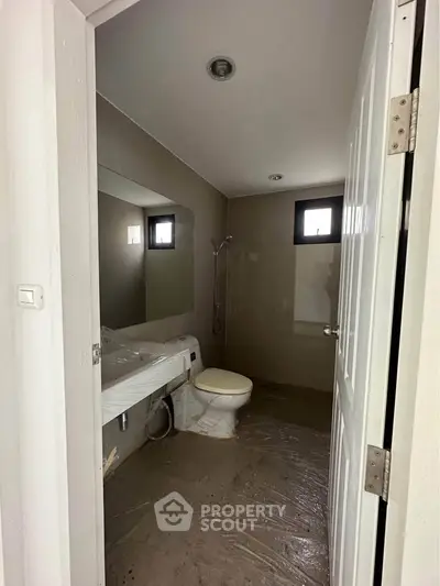 Modern bathroom with sleek fixtures and natural light from small windows.