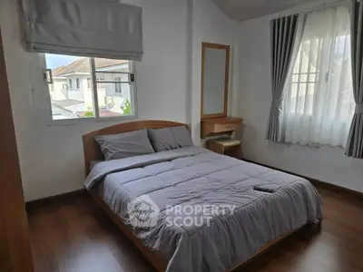 Cozy bedroom with wooden flooring and ample natural light from two windows.