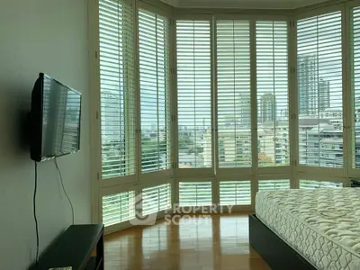 Spacious bedroom with panoramic city view and modern furnishings.