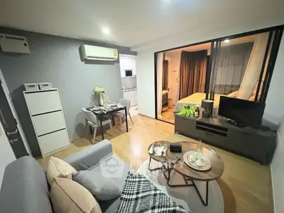Modern living room with cozy seating and open layout leading to bedroom