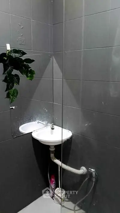 Compact bathroom with modern sink and shower setup, ideal for efficient space utilization.