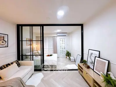 Modern apartment with stylish living room and cozy bedroom separated by glass partition.