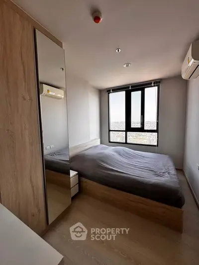 Modern bedroom with large window and city view, featuring sleek wooden furniture and air conditioning.
