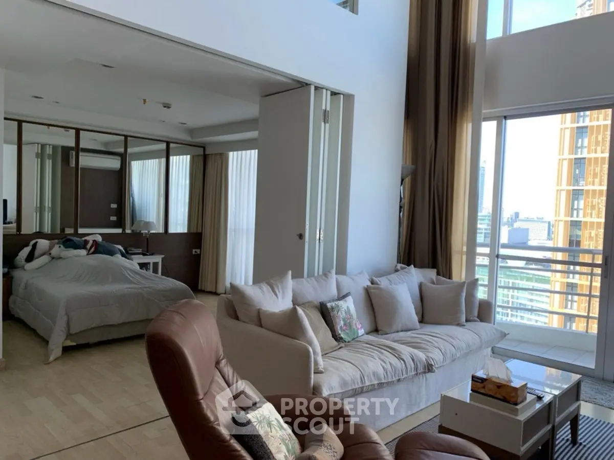 Spacious modern living room with large windows and city view, featuring cozy seating and elegant decor.
