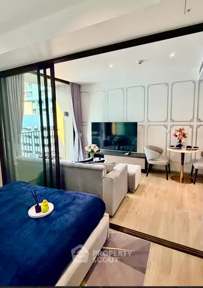 Modern studio apartment with stylish living area and large TV, featuring elegant decor and cozy ambiance.