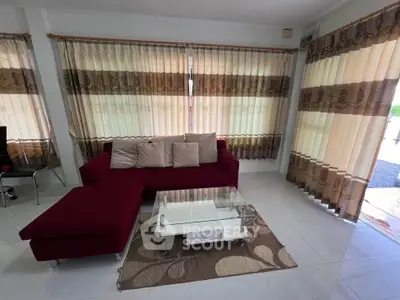 Spacious living room with modern red sofa and elegant curtains