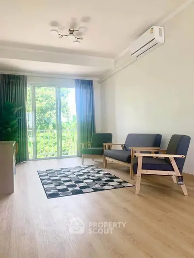 Bright living room with modern furniture and large window overlooking greenery.