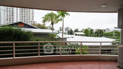 Spacious balcony with lush greenery and city view, perfect for relaxation.