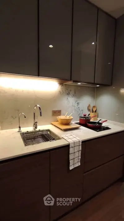 Modern kitchen with sleek cabinetry and under-cabinet lighting, featuring a stylish sink and countertop accessories.