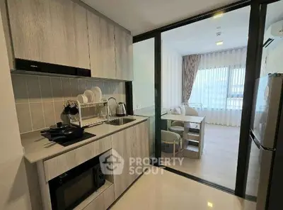 Modern kitchen with sleek cabinetry and open layout leading to a bright dining area.