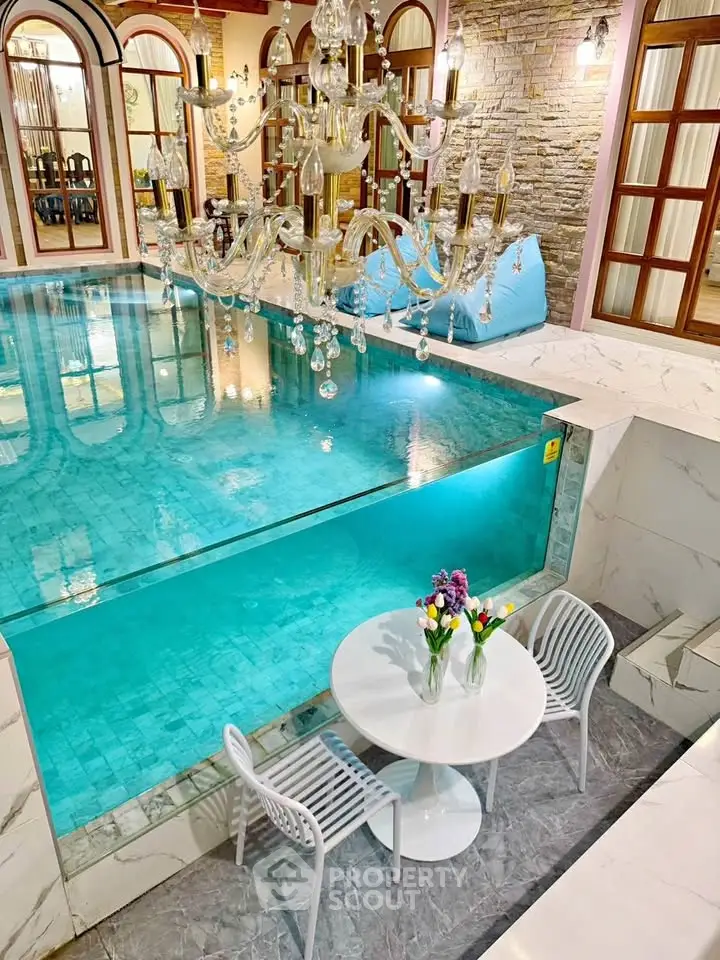Luxurious indoor pool with elegant chandelier and cozy seating area