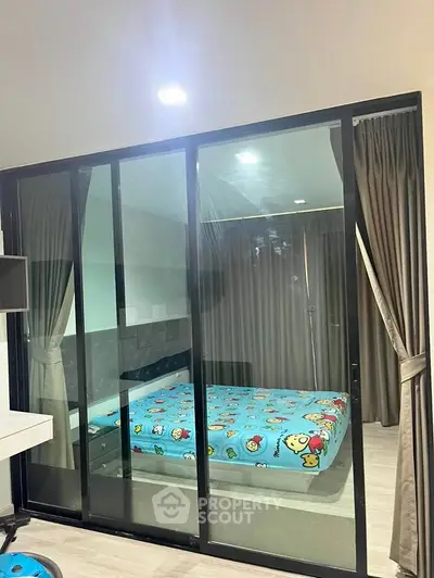 Modern bedroom with glass sliding doors and playful bedding in a stylish apartment.