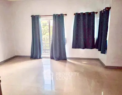 Spacious empty room with large windows and blue curtains, perfect for customization.