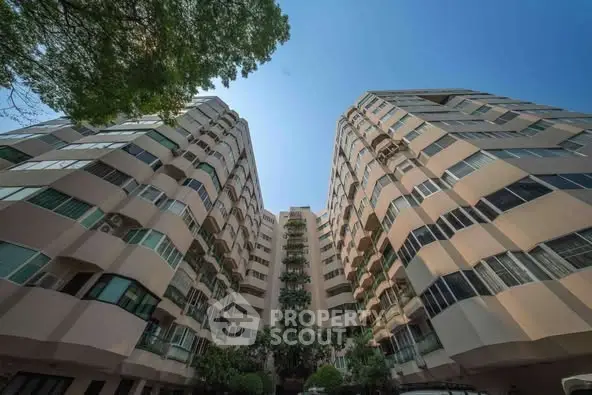 Stunning architectural view of a modern residential building with lush greenery and clear blue sky.