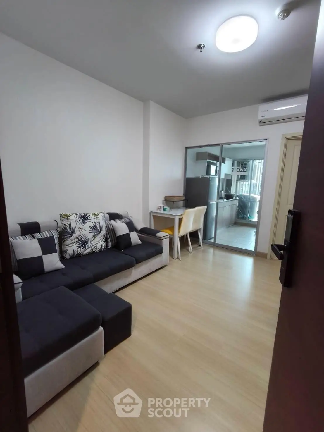 Modern living room with stylish sofa and dining area, featuring sleek wooden flooring and open kitchen view.