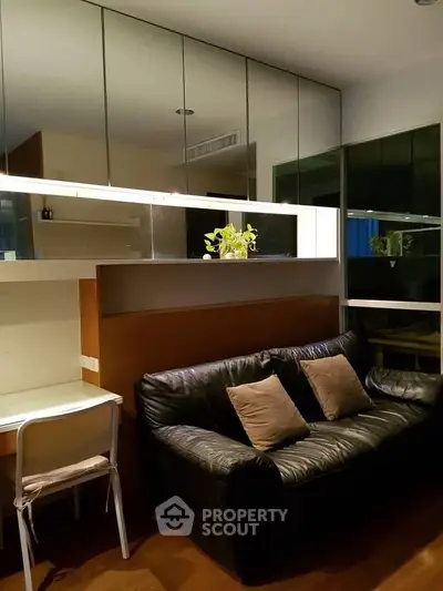 Cozy living room with black leather sofa and mirrored wall