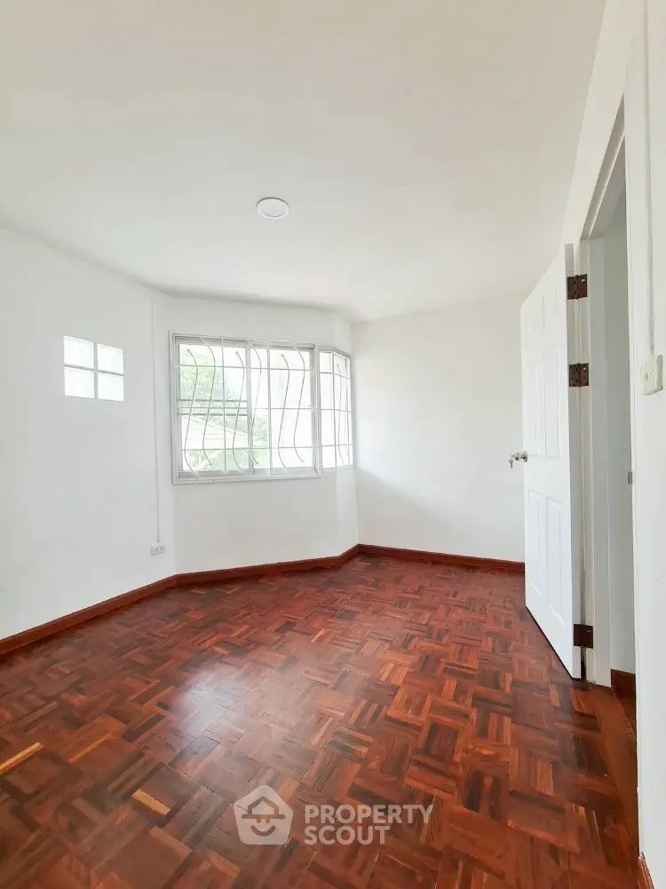 Bright empty room with wooden parquet flooring and large window
