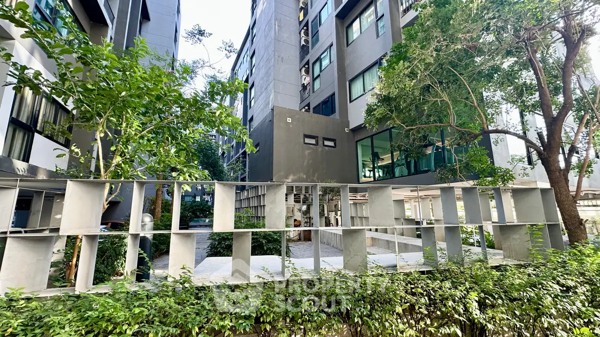 Modern apartment building exterior with lush greenery and unique architectural design.