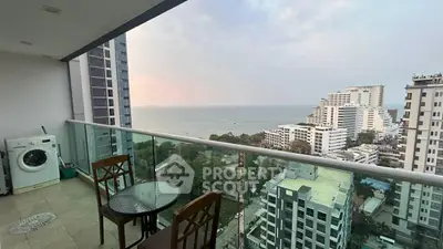 Stunning high-rise balcony with ocean view and cozy seating area.