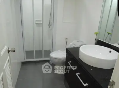 Modern bathroom with sleek black countertop and glass shower enclosure