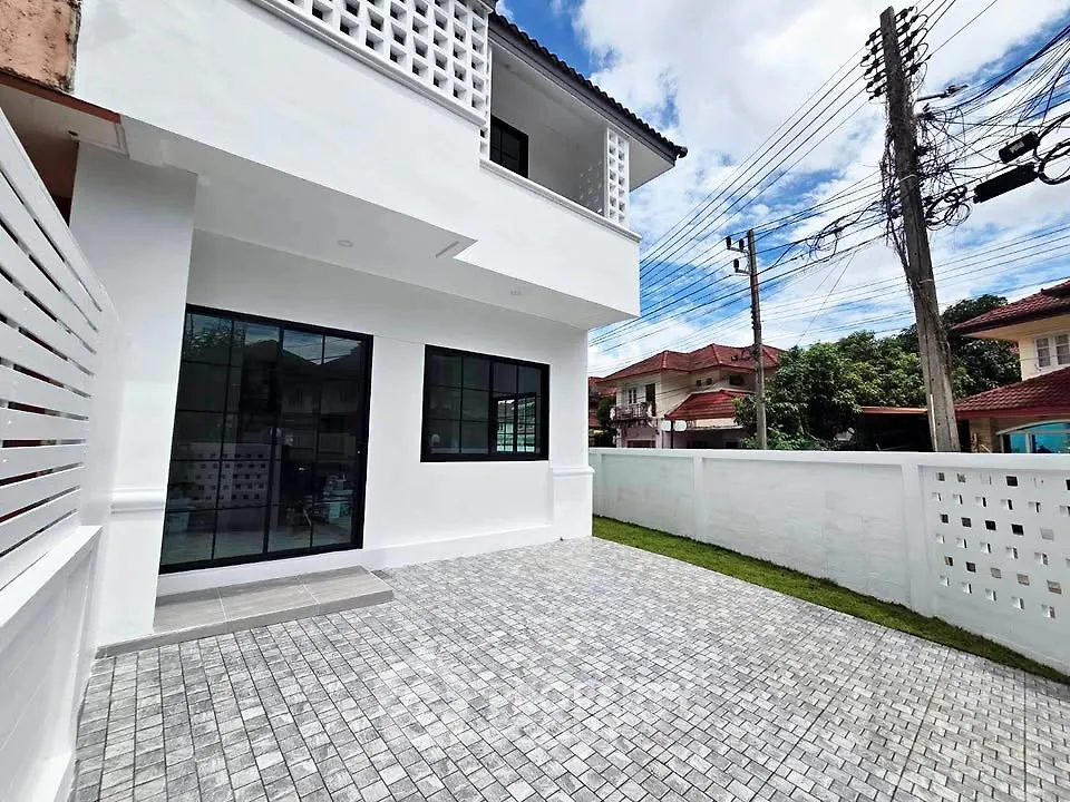 Modern white house exterior with spacious paved driveway and lush green lawn.