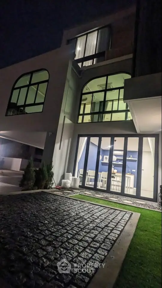 Stunning modern home exterior with large windows and elegant night lighting, showcasing contemporary architectural design.