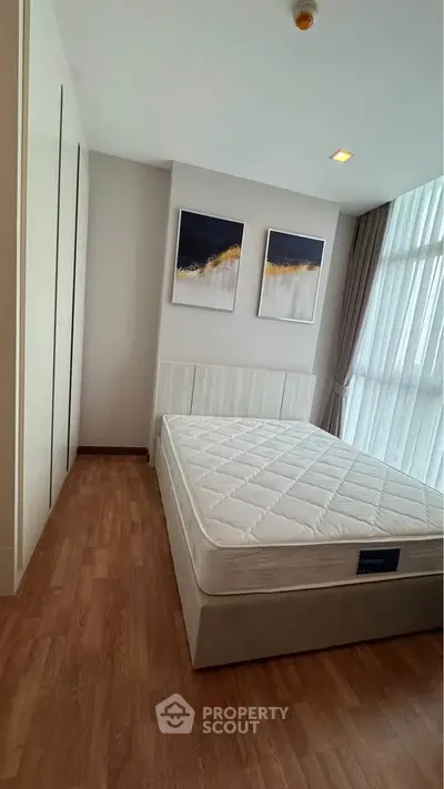 Modern bedroom with large window and stylish decor in a contemporary apartment.