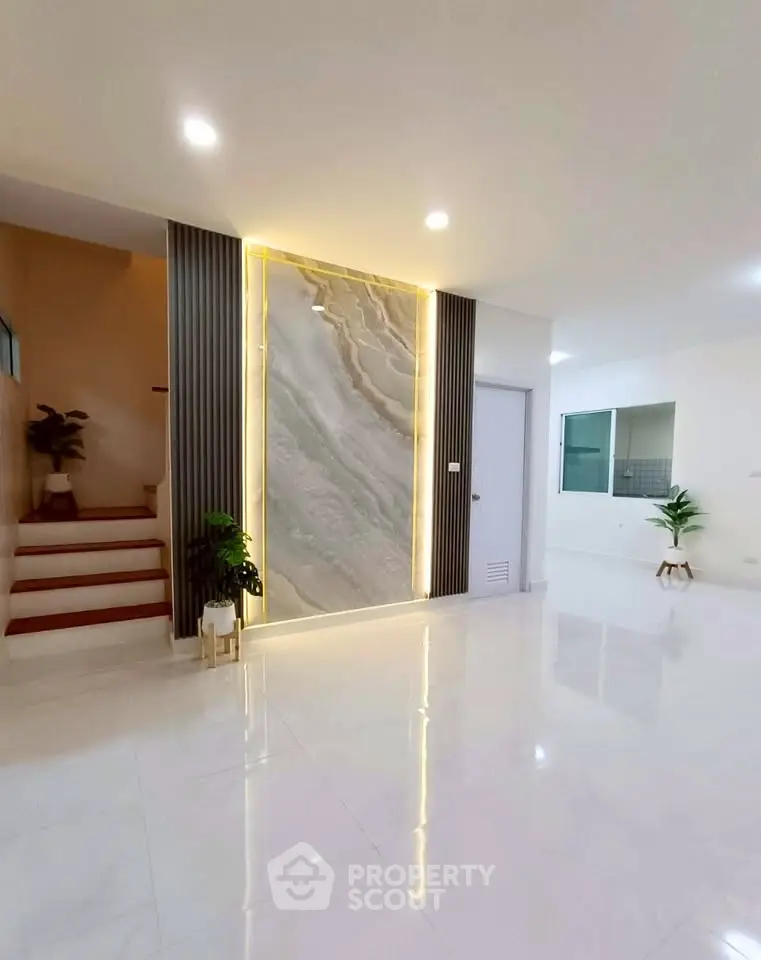 Modern interior with elegant marble accent wall and sleek staircase in a spacious living area.