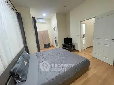Modern bedroom with cozy decor and wooden flooring, featuring a sleek wardrobe and wall-mounted TV.